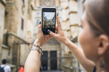 Girl makes a photo or video on the phone. Hands hold a smartphone and make a photo with landmark in the europe old town. Toledo, Spain