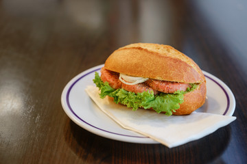 bread roll bun with mettwurst sausage from smoked minced pork with onions and lettuce served as breakfast or fast snack on a plate on a dark wooden table, copy space