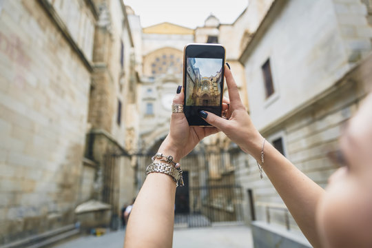 Girl makes a photo or video on the phone. Hands hold a smartphone and make a photo with landmark in the europe old town