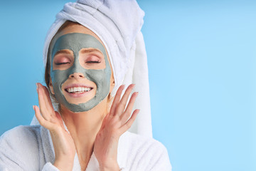 Enjoying woman with purifying mask on her face isolated on blue background