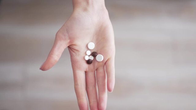 Probiotics, nutritional supplements and vitamins in the hand. The girl shows medical medicines and removes them from the frame. Harmless medicine capsules close up