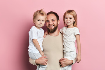 positive father having fun with children, close up portrait, isolated pink background, studio shot,...