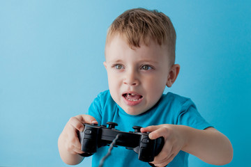 Little kid boy 2-3 years old wearing blue clothes hold in hand joystick for gameson blue background children studio portrait. People childhood lifestyle concept. Mock up copy space