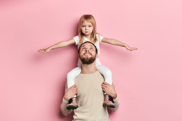 girl pretending a plane while sitting on her father, entertainment concept. close up portrait,...