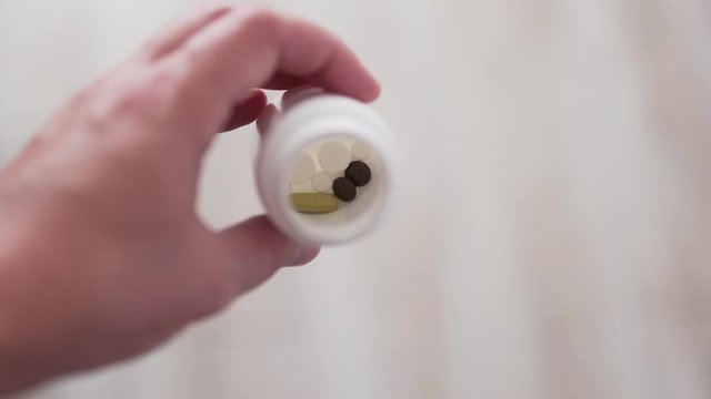 Capsules of drugs in a container close-up in a male hand. Prescription painkiller, sedative and antipyretic