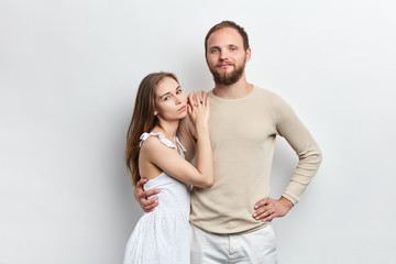 Fototapeta premium young romantic couple looking at the camera, standing over cblue background, studio shot