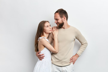 Fototapeta premium girl with long brown hair putting her arms on her guy's shoulder, relies on him, relationship between wife and husband , isolated white background