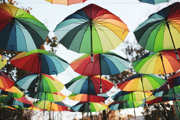 Obraz na płótnie Canvas Rainbow colored umbrellas hang in a public park