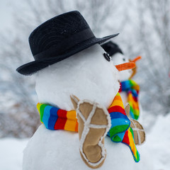 Happy snowman standing in winter Christmas landscape. The snowman is wearing a fur hat and scarf....