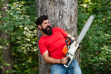 Lumberjack with chainsaw on forest background. Man doing mans job. Lumberjack with chainsaw in his...