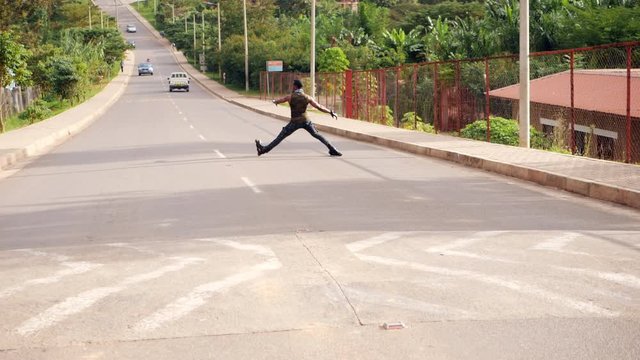 Dexterous young man riding rollerblades in the road doing tricks turning around  in slow motion in  the road during midday in africa