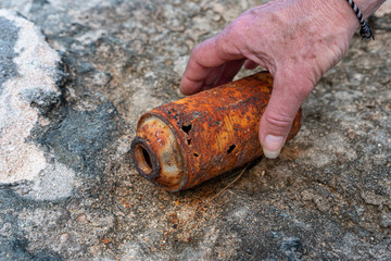 someone picking up a rusted spray can of the ground