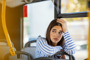 Worried young woman traveling inside of a bus. Beautiful sad woman traveling with bus, hands on...
