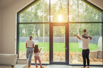 Enjoying family look at window, dream. baby sits on dad's shoulders, daughter stand with mother