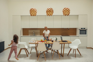 Every day of caucasian family at home. Minimalism interior home. Everybody busy with something. Mother cooking meal for every family member