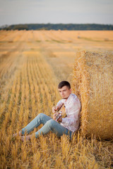 Naklejka na ściany i meble young guy is relaxing in the countryside with a guitar. Plays the guitar . Resting lying on the hay