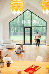 White interior of room, big panoramic windows. Family playing with each other. White colors....