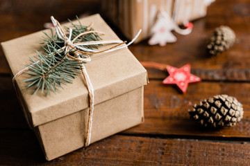 Wrapped and packed giftbox with conifer on top on wooden table