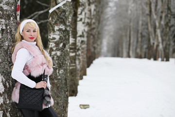 Blonde girl on a walk in a winter park