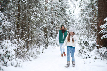 Young family for a walk. Mom and daughter are walking in a winter park.