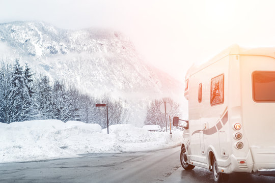 Caravan or campervan turning from road with beautiful mountain alpine landscape on background at cold winter season.Family vacation travel, holiday trip in motorhome. Beautiful austrian nature scene