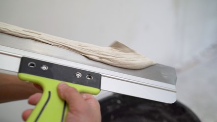 Master applies putty with a spatula. The process of applying the second layer of putty trowel for light plaster walls