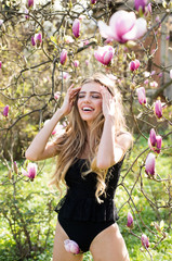 Beautiful and fashionable model girl in the garden. Fashion model woman. Beauty young blonde model with perfect make-up and perfect hair. Magnolia. Laugh. Smiling. Happy.