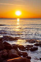 Obraz premium Scenic rocky beach Cala Violina landscape at the sunset. The sun is going down behind the horizon. Tyrrhenian Sea bay at the sunset.