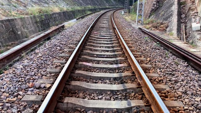 4K - The bending Railway line is carried over gravel and concrete sleepers, slow motion to  a railway tunnel. Source from  60 FPS footage.