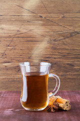 hot tea in glass cup with cinnamon on wood background.