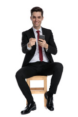 Handsome businessman pointing forward and holding his phone