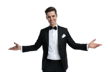 smiling elegant groom in tuxedo opening arms and welcoming