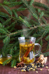 Winter chamomile hot tea with honey, cinnamon and christmas tree branch on wood background.
