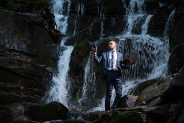 Waterproof technology. Man with notebook stand near waterfall. Modern technology. Successful businessman follow flow. Guy formal style hold laptop. Wireless technology. Work in nature concept