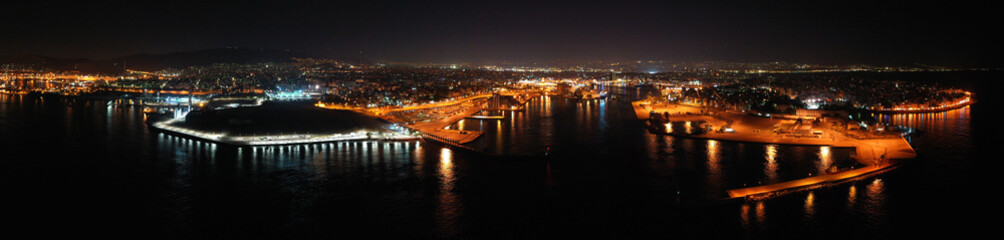 Fototapeta na wymiar Aerial drone night shot of beautiful illuminated port of Piraeus and huge cruise liner departing to Aegean popular destinations, Attica, Greece