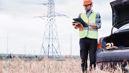 A man in a helmet and uniform, an electrician in the field. Professional electrician engineer...