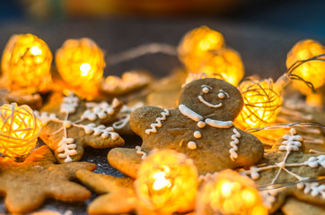 Smiling gingerbread man lies among cookies and rattan New Year garlands on the festive table