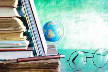 Education concept. A stack of textbooks and a book on the desk with glasses and a computer. School breakfast apple and homework.