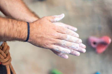 Close up of climber man coating hands in powder chalk magnesium and preparing to climb workout outdoor training rock wall . - Powered by Adobe