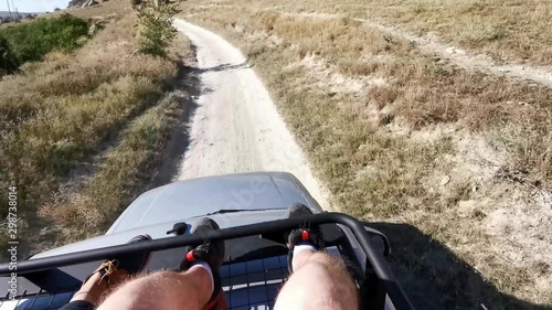 Wall mural Riding on the roof of a car on a dusty rural road. POV 4K video.