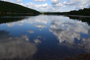 clear water of the Vishera River and clouds reflected in it