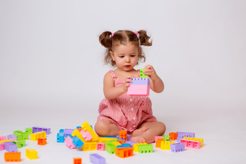 baby girl playing with multicolored constructor, isolate, space for text