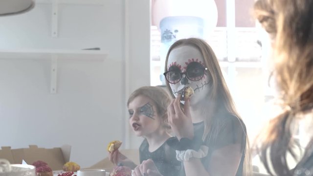 Festive Halloween party in process - kids are sitting next to the table and have tasty treats.