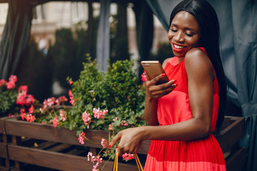 Black girl in a summer city. Woman with a shoping bags. Lady in a red ress
