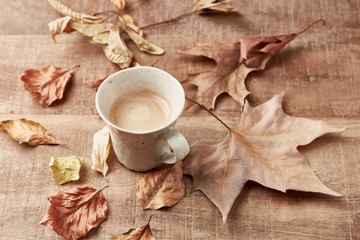 Obraz na płótnie Canvas Mug of coffee and autumn leaves. Rustic wooden background. Copy space. 