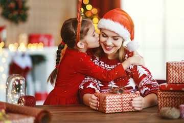 happy family mother and child pack Christmas gifts at home near Christmas tree