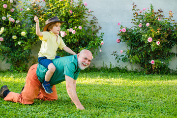 Senior man with grandson jogging in park. Cute child boy hugging his grandfather. Child with...
