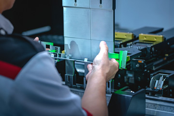 Workers bending sheet metal by CNC machines in industrial plants