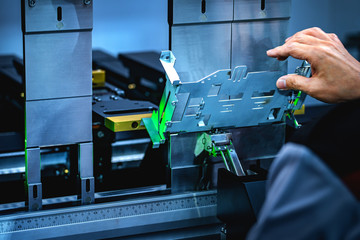 Workers bending sheet metal by CNC machines in industrial plants