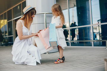 Beautiful girl in a summer city. Lady with shopping bags. Mother with daughter in stylish clothes